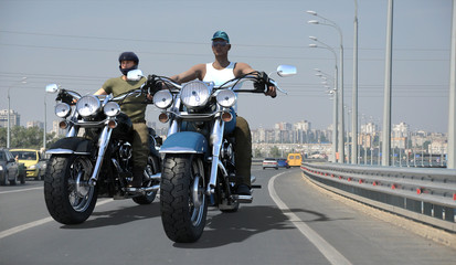 Young handsome bikers riding motorcycles on a wide city road. 3d render.