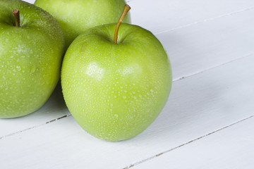 Close-up of green beautiful apples on white wooden desk