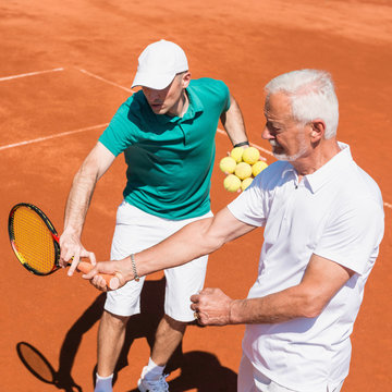 Senior man with having a tennis lesson with instructor