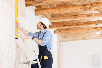 Builder using consruction level and standing n the ladder