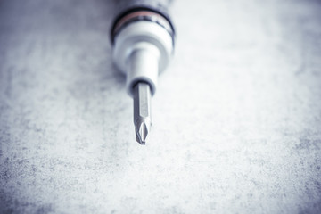 Screwdriver with bits in close up on stone workbench. Tool for diy work and repair. Macro shot of construction equipment.