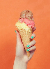 Woman hand holding ice cream on orange background
