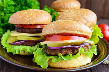 Many hamburgers at home (bun, tomato, cucumber, onion rings, lettuce, pork chops, cheese) in a clay bowl on a wooden background. Close-up
