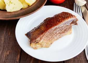 Juicy piece of roast goose on a white plate. close-up.
