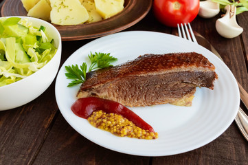 Juicy piece of roast goose on a white plate. close-up.
