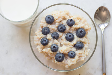 Bowl of oatmeal porridge with blueberry on marble table
