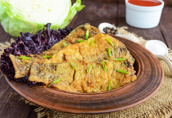 Fried carp fish fillet in batter on wooden table. Close-up