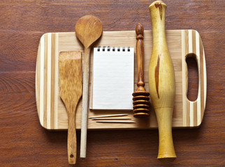 A method of presenting a cooking recipe: a notebook for writing prescriptions and wooden kitchen utensils. Culinary background