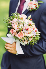 Groom holding roses bouquet, close up