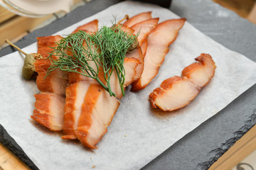 Slices of smoked fish with dill on a tray.
