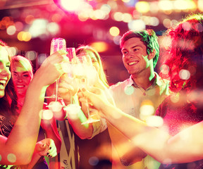 Obraz na płótnie Canvas smiling friends with glasses of champagne in club