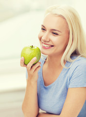 happy woman eating green apple at home