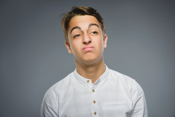 Closeup Portrait of handsome boy with astonished expression while standing against grey background