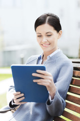 smiling business woman with tablet pc in city