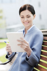 businesswoman reading notes in notepad outdoors