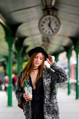 Young beautiful pretty girl walking along the street with handbag and cup of coffee.