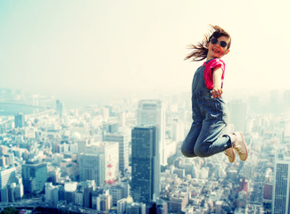 Fototapeta na wymiar happy little girl jumping over city background