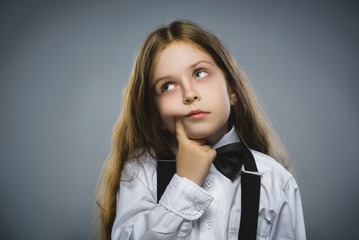 Closeup Thoughtful Young girl Looking Up with Hand at Face isolated on Gray Background