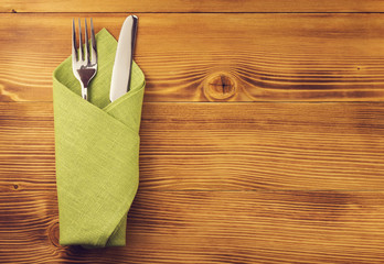 knife and fork at napkin on wood