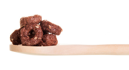 Crispy corn rings with cocoa, sesame seeds in  wooden spoon.