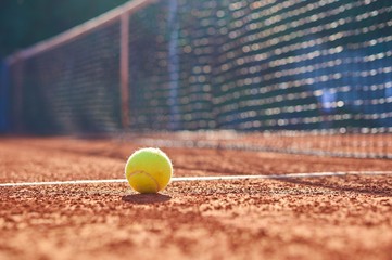Tennis ball on court with blurred background.