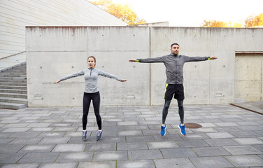 happy man and woman jumping outdoors