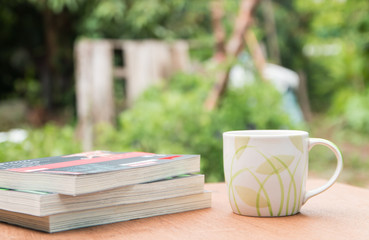 a cup of coffee and books on the wooden table