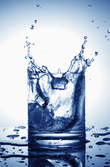 Ice cubes splashing into glass of water