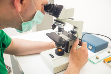 veterinarian or doctor checking up sample with microscope