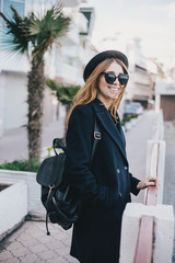 Fototapeta premium Young beautiful woman wearing hat and coat standing on the embankment near sea