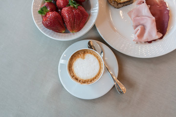 Top view of Cappuccino with strawberries , ham , bacon background 