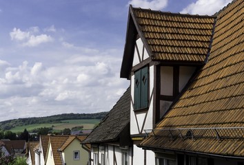 Dachgaube eines alten Fachwerkhauses mit Blick auf entfernte Viehweiden und Felder