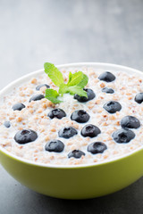 Buckwheat porridge in a bowl with mint leaves and blueberries.