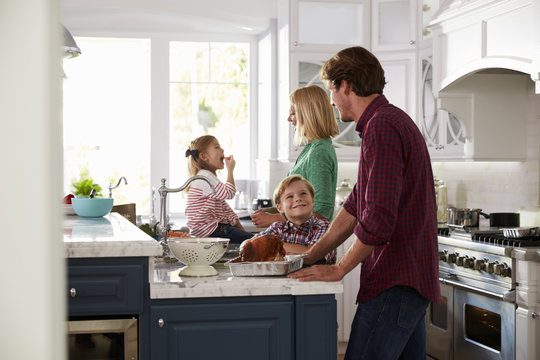 Family Preparing Roast Turkey Meal In Kitchen Together