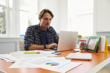 Man Sitting At Desk Working At Laptop In Home Office