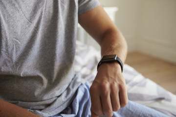 Man Wearing Pajamas Checking Smart Watch In Bedroom