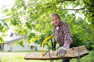 Senior man sawing a log handsaw closeup