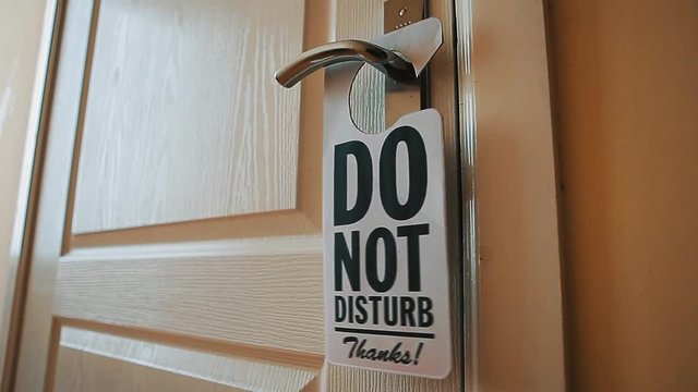 Swinging Do No Disturb sign at hotel room door