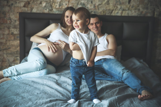 Pregnant women with her husband and daughter on the bed