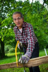 Senior man sawing a log handsaw closeup