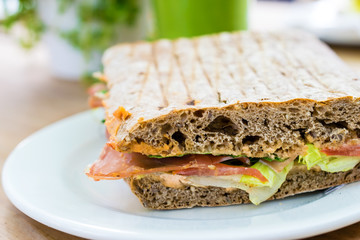 Sandwich serviert with smoothie on wooden table.