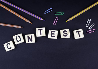 Contest. Text from wooden letters on a black office desk.