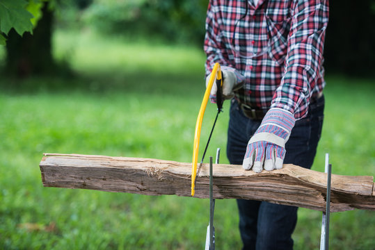 Senior man sawing a log handsaw closeup