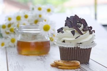 Muffin. Cupcake with chocolate and honey and daisy flower.