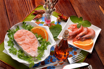 salmon dishes and raw shrimp surrounded with parsley and orange