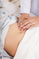 Stomach examination, doctor's hands pressing woman's stomach for examination