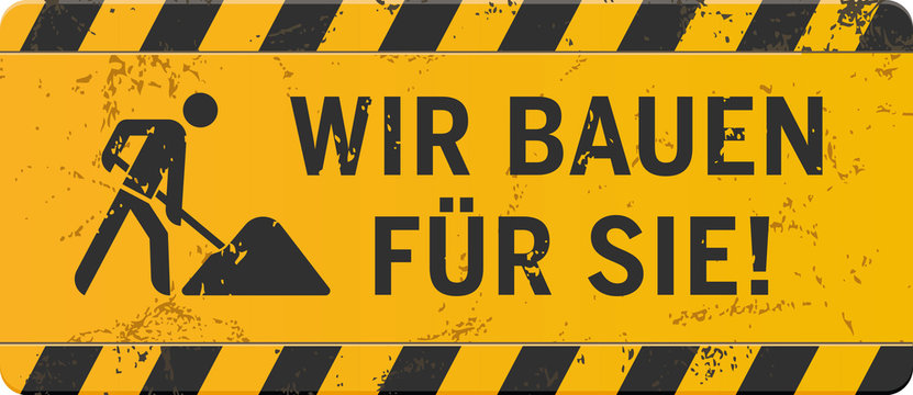 gelbes Schild Wir bauen f&uuml;r Sie mit Bauarbeiter-Icon zerkratzt

