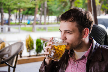 Man drinks beer. Side view of handsome young guy drinking lager pint while sitting at the bar counter