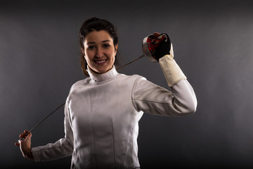 Portrait of woman wearing white fencing costume practicing with the sword.