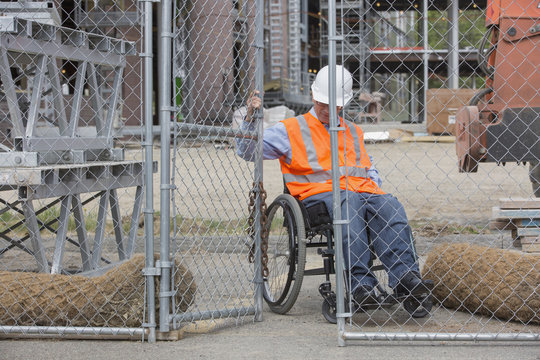 Engineer in wheelchair opening construction site gate